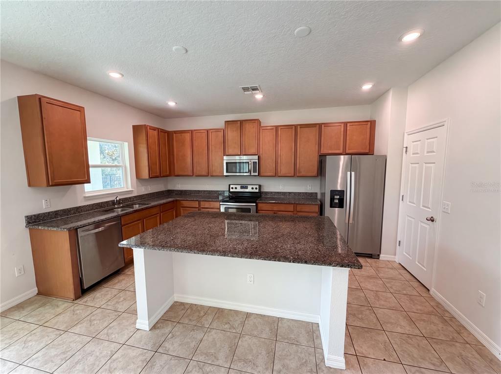 A kitchen features wood cabinets, granite countertops, stainless steel appliances, and a central island — 811 MAPLE LEAF LOOP, WINTER SPRINGS, FL