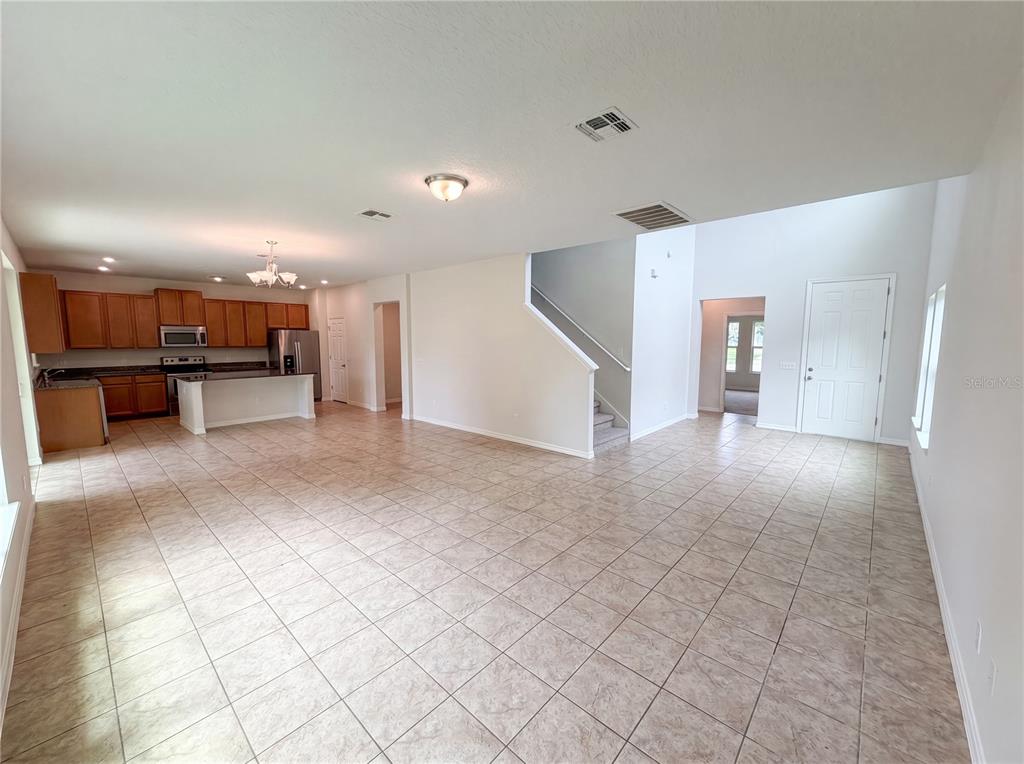 An open-concept living area features tile flooring, a kitchen with wood cabinets, and a staircase — 811 MAPLE LEAF LOOP, WINTER SPRINGS, FL