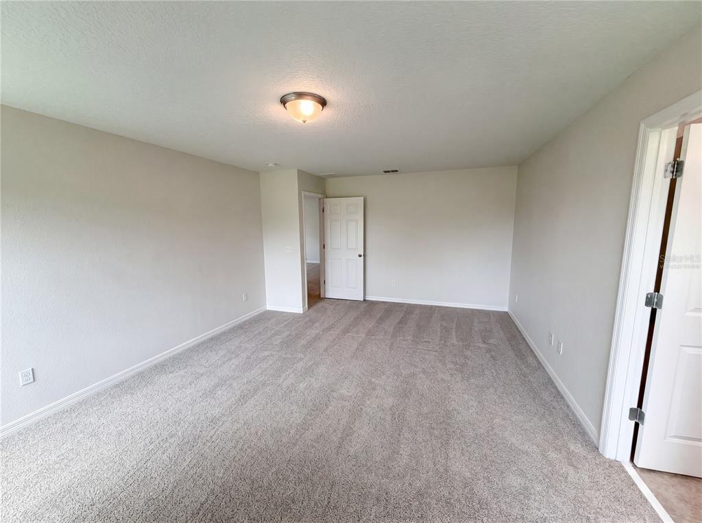 An empty bedroom features beige walls, gray carpet, a ceiling light, and two white doors — 811 MAPLE LEAF LOOP, WINTER SPRINGS, FL