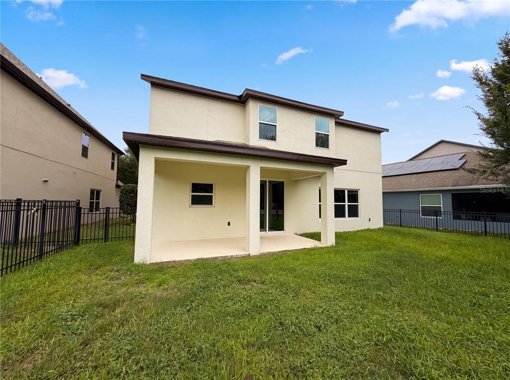 The rear exterior of a two-story house features a covered patio and a fenced yard — 811 MAPLE LEAF LOOP, WINTER SPRINGS, FL