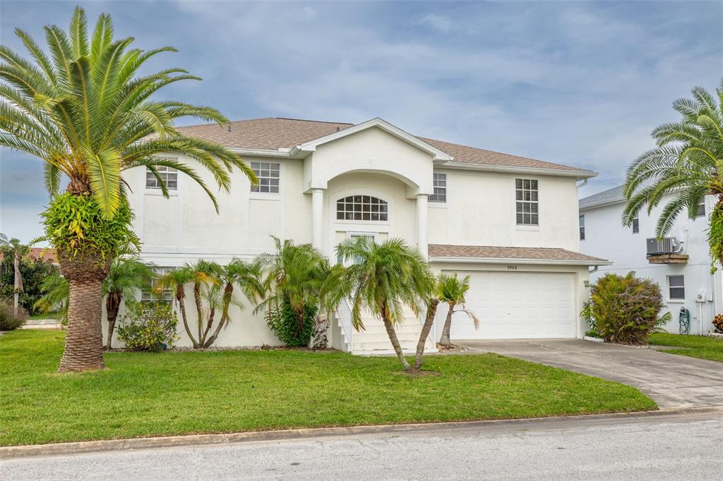 A two-story white house with a garage, palm trees, and a front lawn — 9908 SAN SIERRA WAY, PORT RICHEY, FL