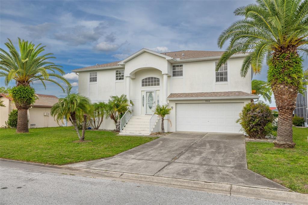 A two-story white house with a two-car garage, front stairs, and palm trees — 9908 SAN SIERRA WAY, PORT RICHEY, FL