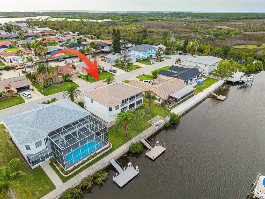 An aerial view shows waterfront houses with docks, swimming pools, and screened lanais — 9908 SAN SIERRA WAY, PORT RICHEY, FL