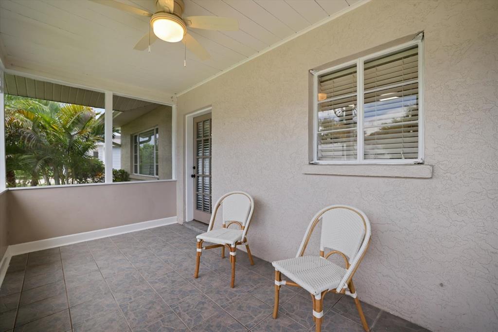 A covered patio features tiled flooring, two white chairs, a ceiling fan, and a window — 2126 HYDE PARK STREET, SARASOTA, FL