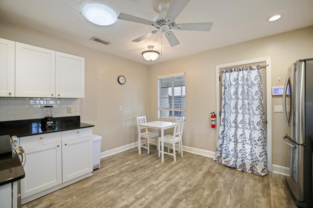 A kitchen with white cabinets, black countertops, a small dining table, and wood-look flooring — 2126 HYDE PARK STREET, SARASOTA, FL