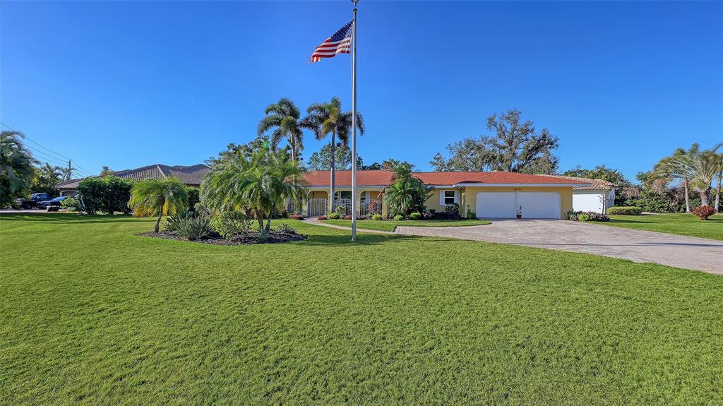 A single-story house with a red roof, white garage doors, and an American flag pole — 844 MAGELLAN DRIVE, SARASOTA, FL