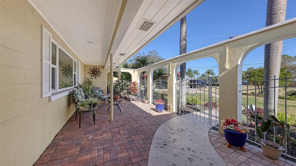 A covered brick patio features arched openings, a metal fence, and potted plants — 844 MAGELLAN DRIVE, SARASOTA, FL