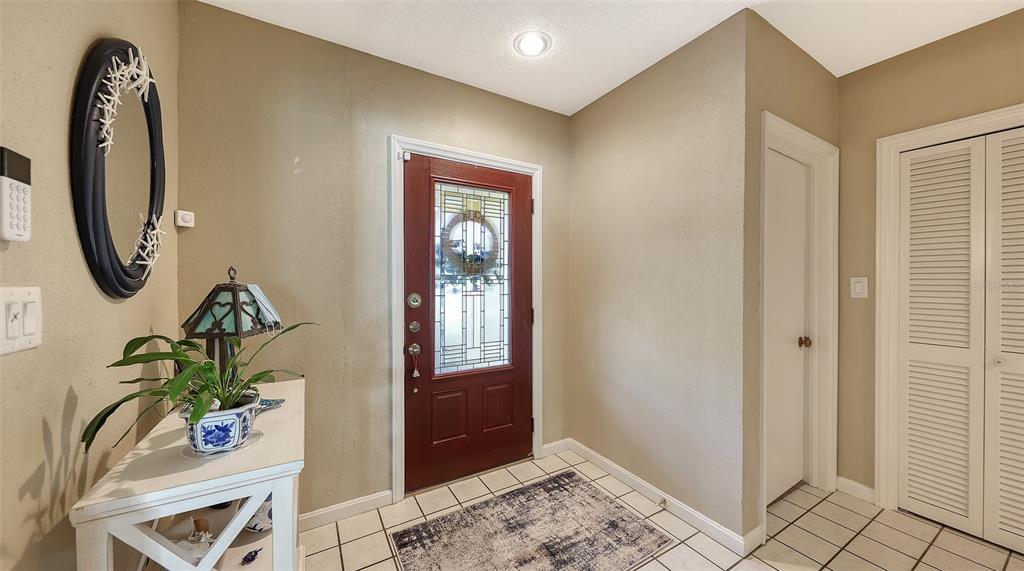 An entryway features a red front door, tiled floors, a console table, and a mirror — 844 MAGELLAN DRIVE, SARASOTA, FL