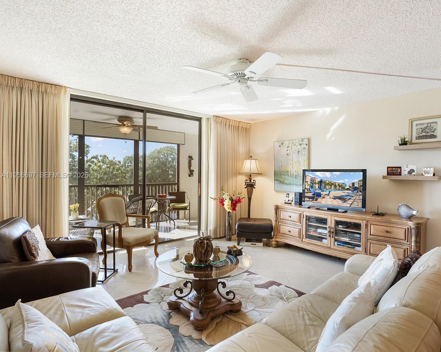 A living room features a white sofa, leather armchair, glass coffee table, and sliding glass doors — 3591 Environ Blvd # A404, Lauderhill FL 33319, LAUDERHILL, FL