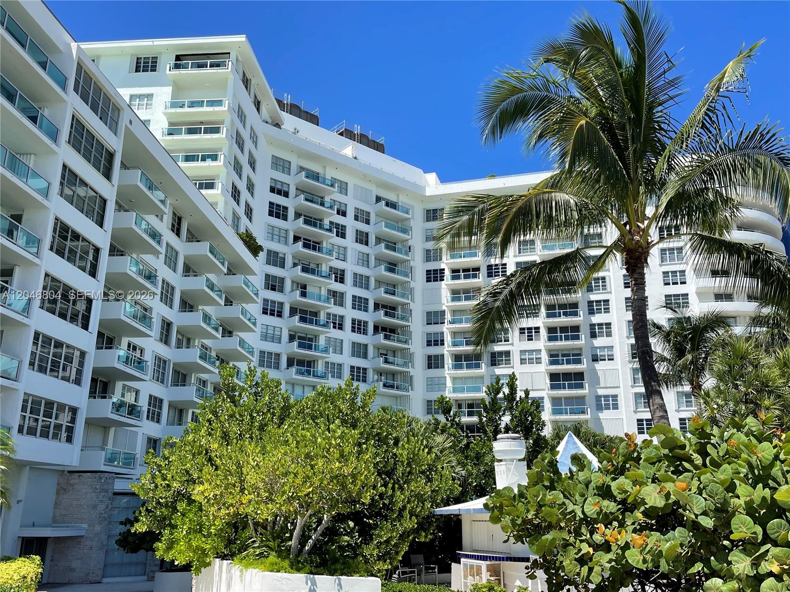 A multi-story white residential building features numerous balconies and is surrounded by lush greenery — 5151 Collins Ave # 1722, Miami Beach FL 33140, MIAMI BEACH, FL