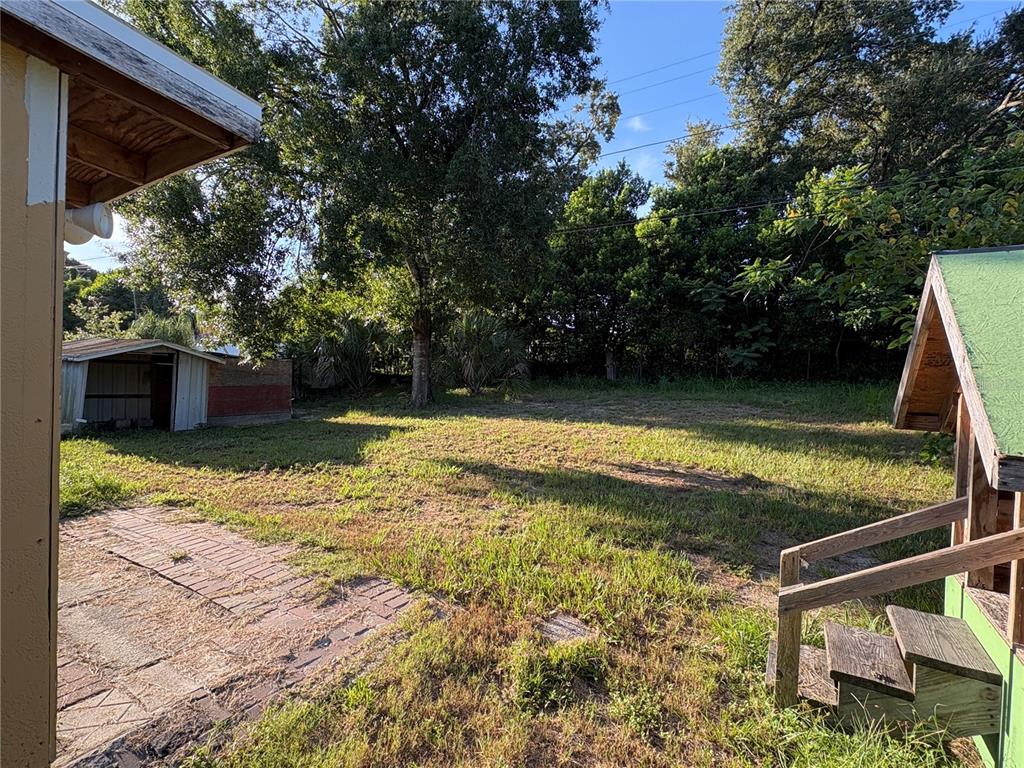 A backyard features a brick patio, a small shed, and a wooden playhouse on grass — 3514 CALLOWAY DRIVE, ORLANDO, FL