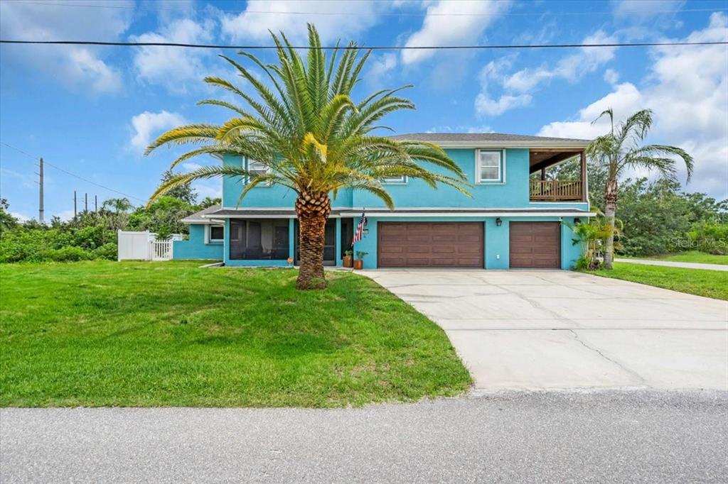 A two-story, bright blue house with a large palm tree and a concrete driveway — 27450 SAN MARCO DRIVE, PUNTA GORDA, FL