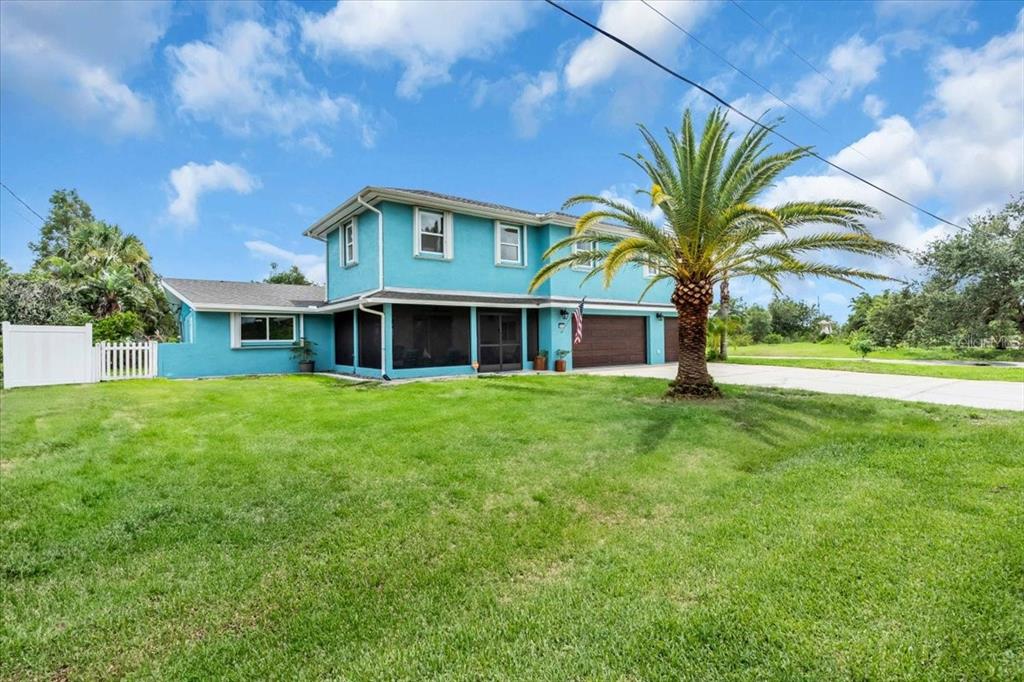 A two-story turquoise house with a screened-in porch, a palm tree, and a grassy yard — 27450 SAN MARCO DRIVE, PUNTA GORDA, FL