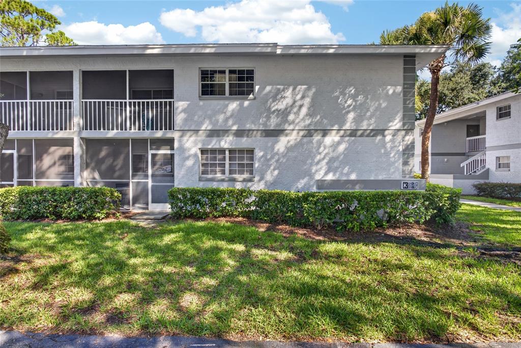 A two-story apartment building exterior with a screened balcony and a small hedge — 563 MIDWAY TRAK UNIT K102, OCALA, FL