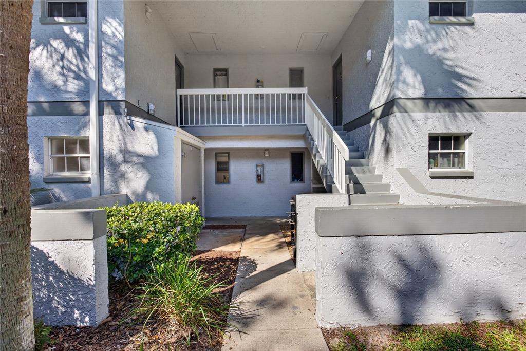 An exterior view of a two-story apartment building with a concrete staircase and walkway — 563 MIDWAY TRAK UNIT K102, OCALA, FL