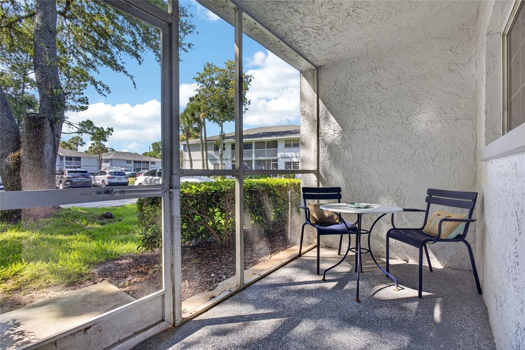 A screened-in patio features a small bistro table and two chairs on a concrete floor — 563 MIDWAY TRAK UNIT K102, OCALA, FL