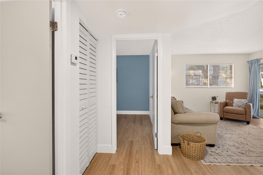 A hallway with wood-look flooring leads to a blue-walled room and an adjacent living area — 563 MIDWAY TRAK UNIT K102, OCALA, FL