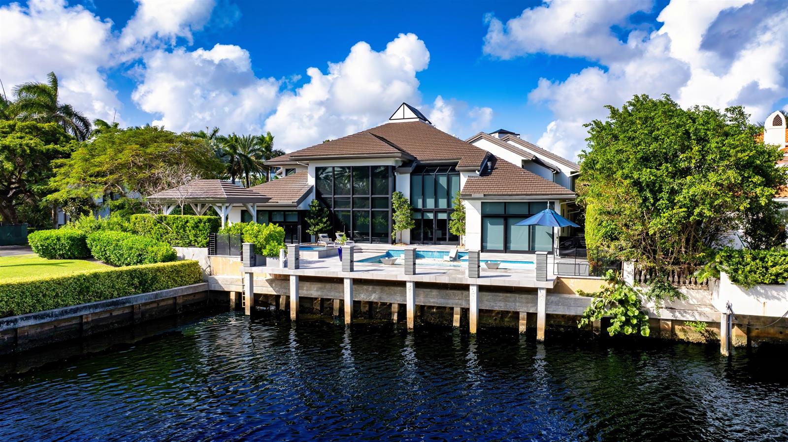 A waterfront house with a pool, patio, and large windows overlooking a canal — 4698 Sanctuary Lane, Boca Raton FL 33431, BOCA RATON, FL