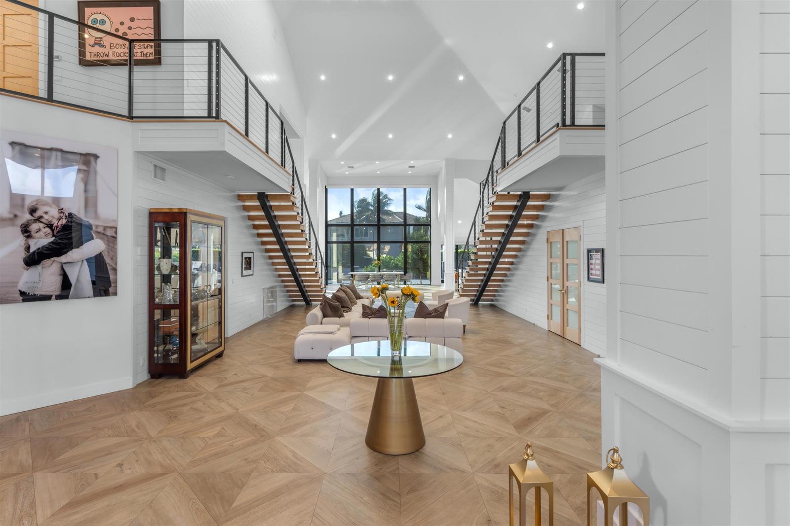 A spacious living room features dual staircases, high vaulted ceilings, and light wood flooring — 4698 Sanctuary Lane, Boca Raton FL 33431, BOCA RATON, FL