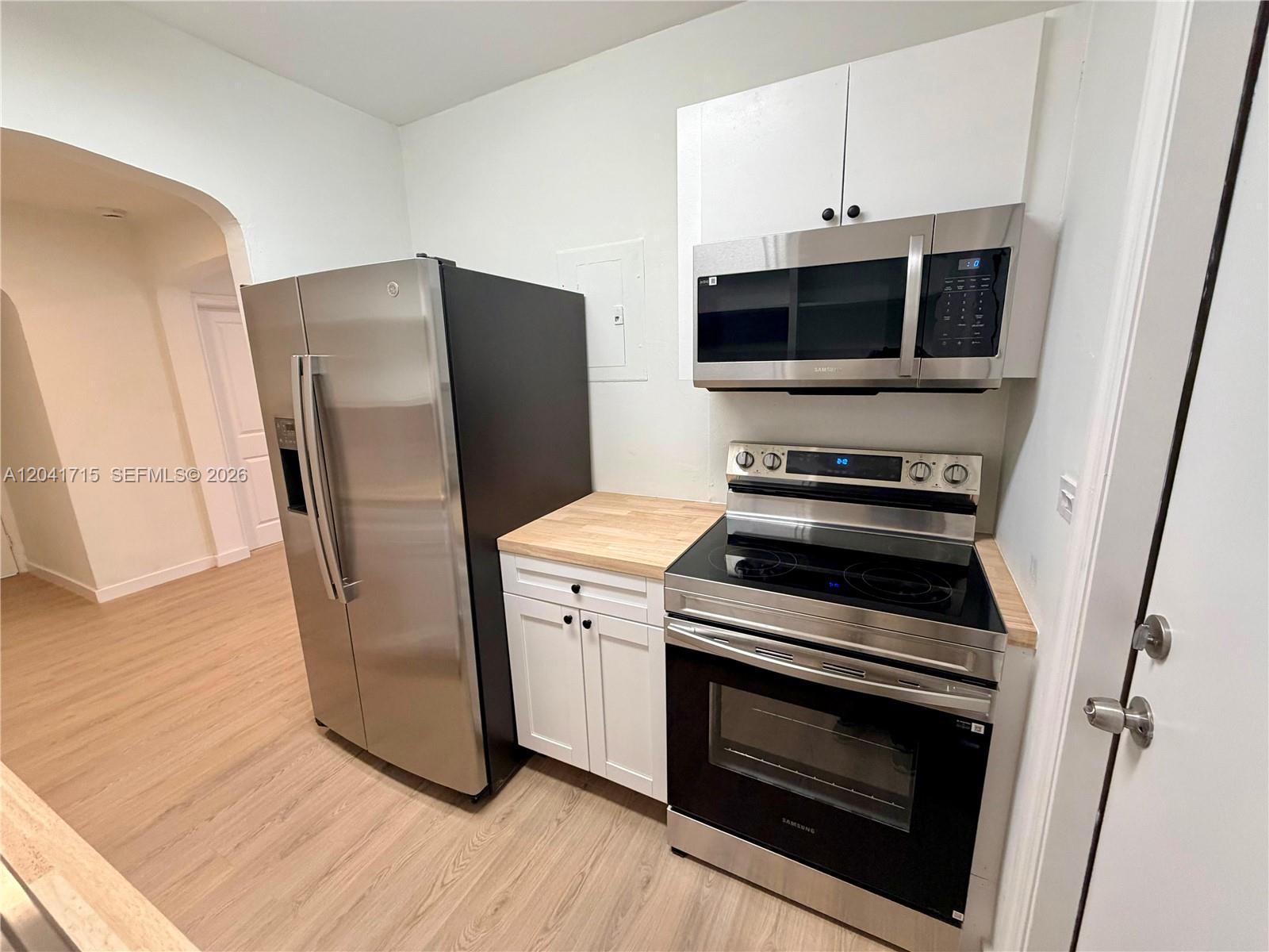 A kitchen features stainless steel appliances, white cabinets, and light wood-look flooring — 255 NW 32nd St, Miami FL 33127, MIAMI, FL