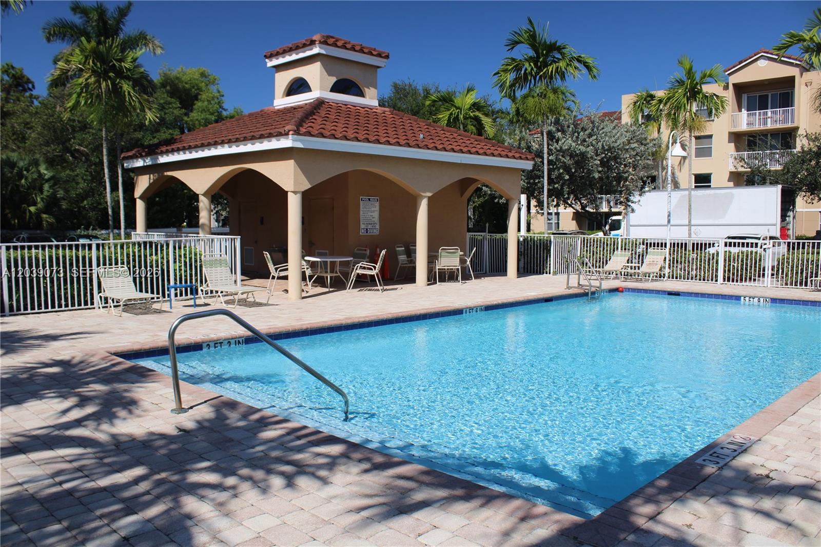 An outdoor swimming pool with a covered pavilion and lounge chairs on a sunny day — 519 E Sheridan St # 1082, Dania Beach FL 33004, DANIA BEACH, FL