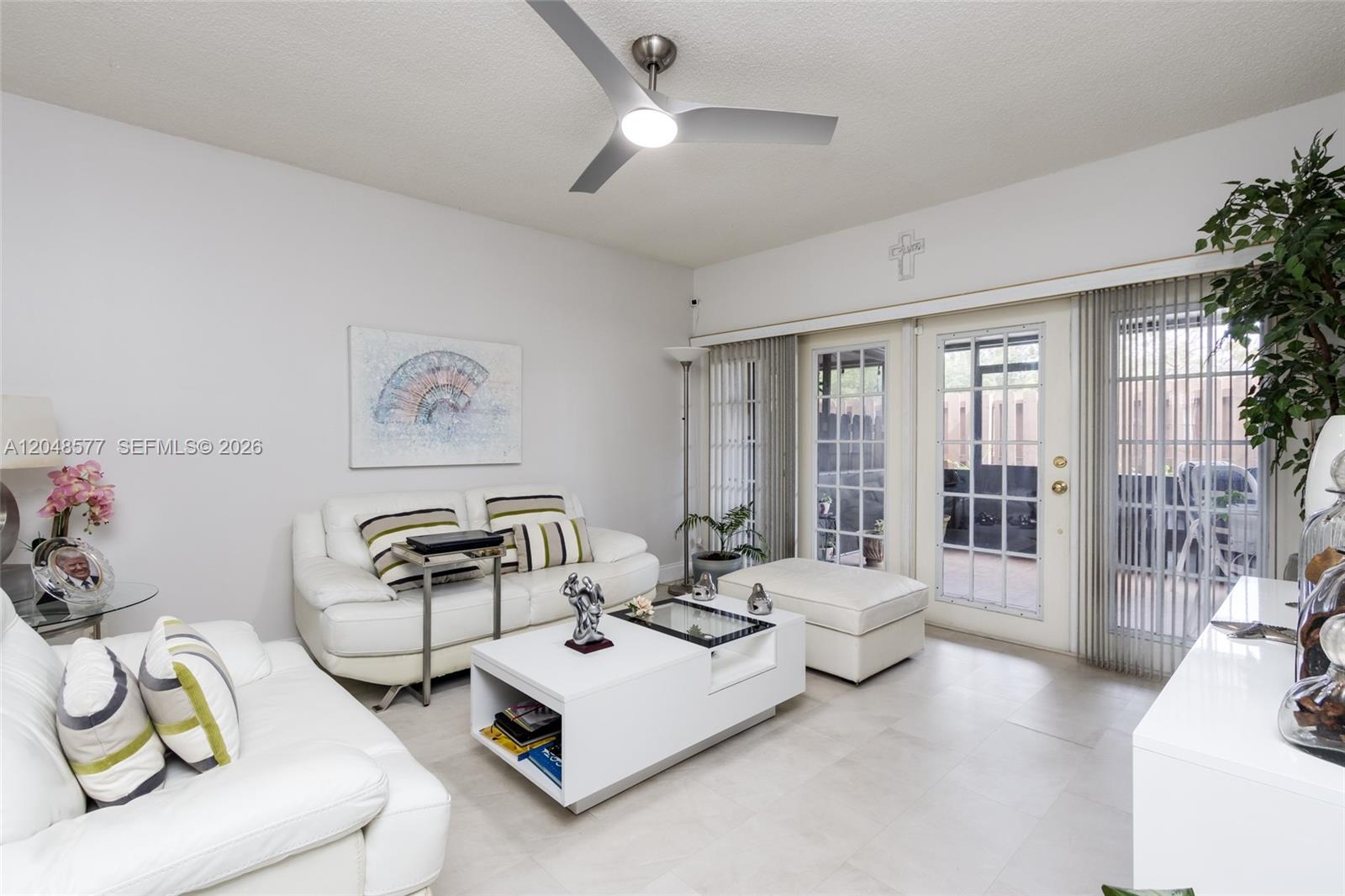 A bright living room features white leather sofas, a modern coffee table, and glass doors — 7032 SW 23rd St # 16, Davie FL 33317, DAVIE, FL