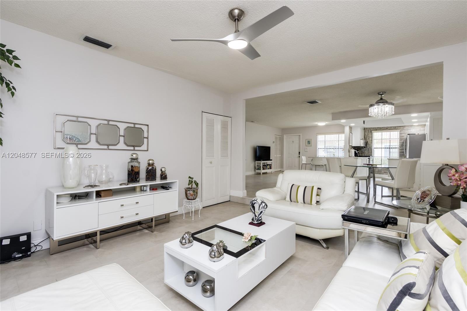 A bright living room features white furniture, a modern ceiling fan, and tile flooring — 7032 SW 23rd St # 16, Davie FL 33317, DAVIE, FL