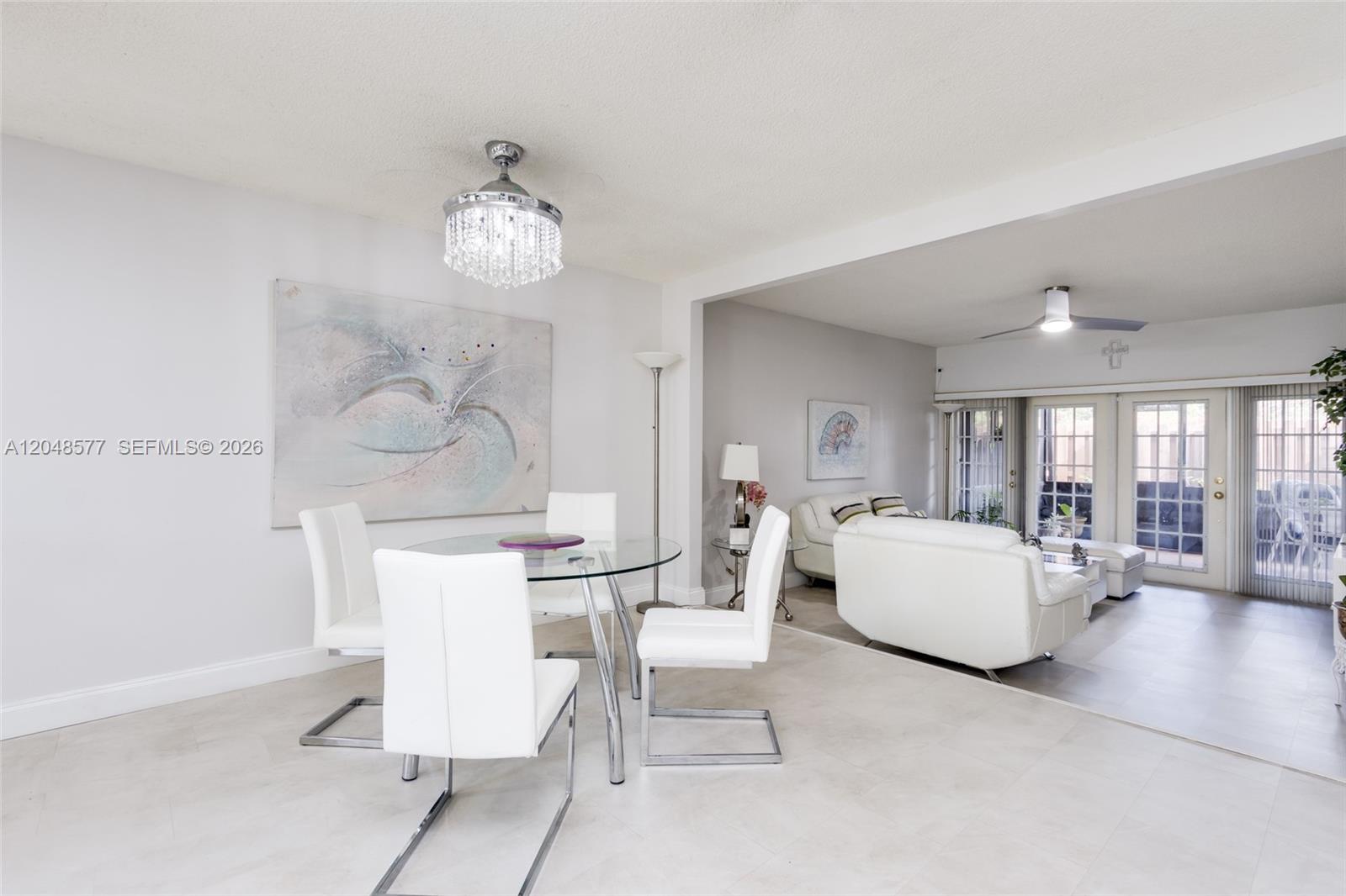A dining area with a glass table and white chairs opens into a living room — 7032 SW 23rd St # 16, Davie FL 33317, DAVIE, FL