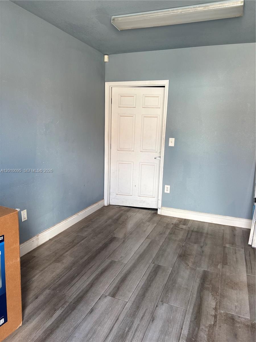 A room with blue walls, wood-look flooring, and a white six-panel door — 16300 SW 137th Ave # 116, Miami FL 33177, MIAMI, FL