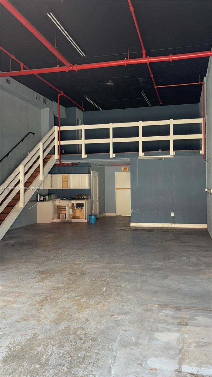 An industrial-style space features a concrete floor, a wooden staircase, a loft, and a kitchenette — 16300 SW 137th Ave # 116, Miami FL 33177, MIAMI, FL