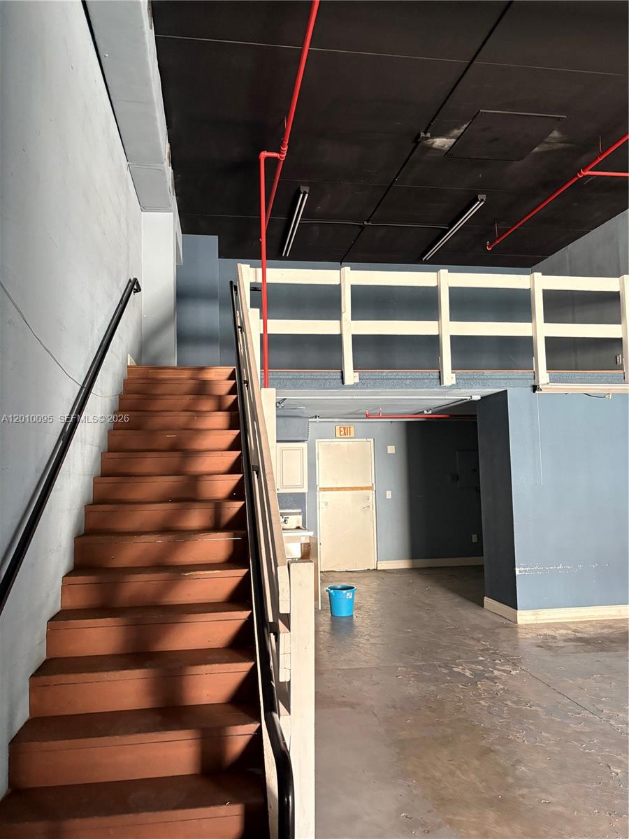 A staircase leads to a loft area in an industrial-style room with exposed pipes — 16300 SW 137th Ave # 116, Miami FL 33177, MIAMI, FL