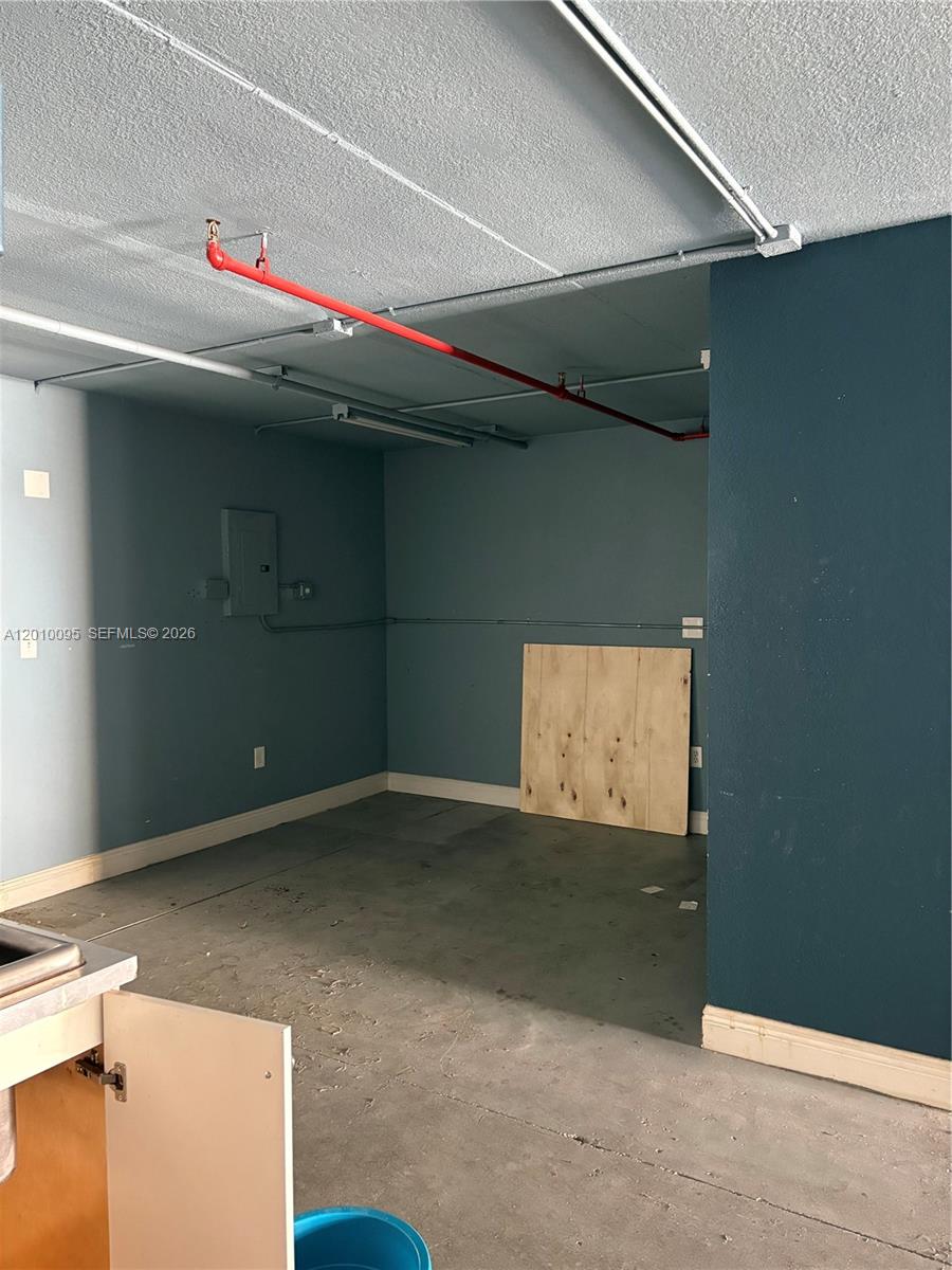 An unfinished utility room features exposed red fire sprinkler pipes and blue-painted walls — 16300 SW 137th Ave # 116, Miami FL 33177, MIAMI, FL