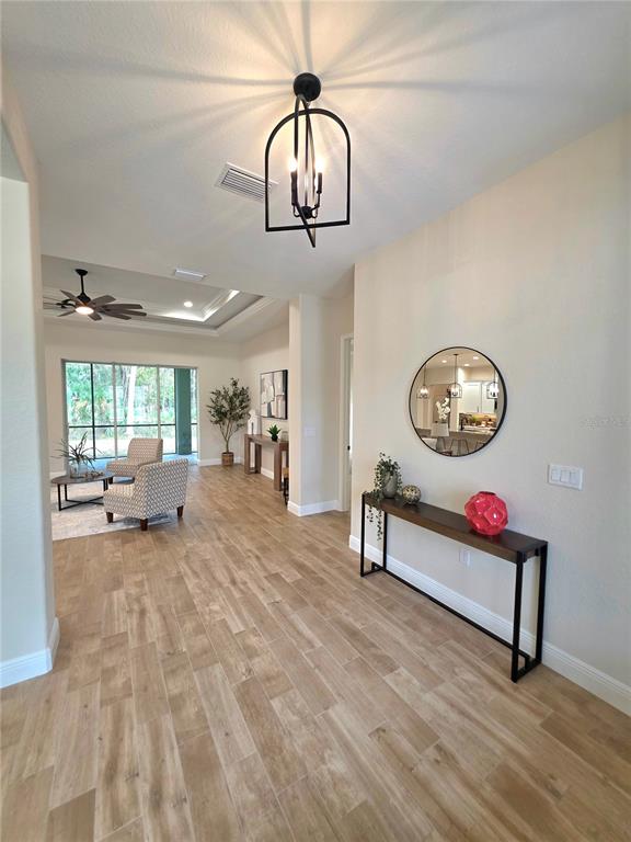 A foyer with wood-look tile flooring leads into a living area with a ceiling fan — 13444 REPUBLICAN WAY, BROOKSVILLE, FL