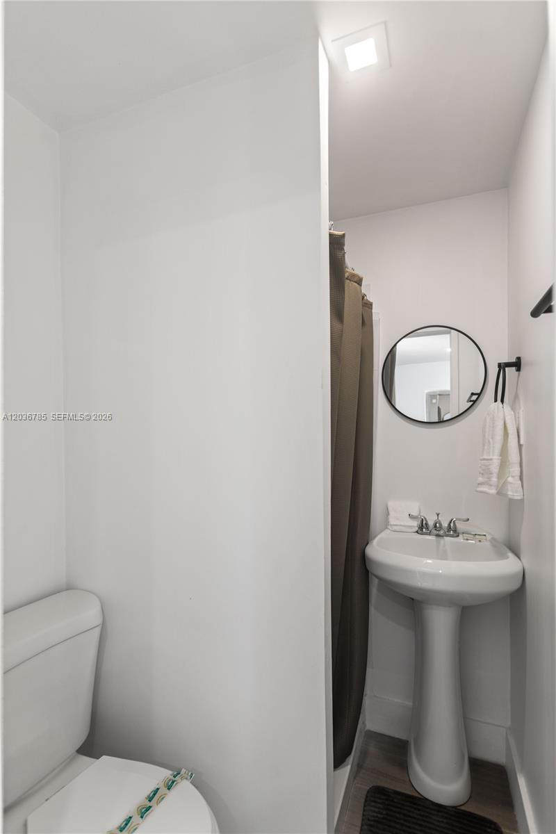 A small bathroom features a pedestal sink, a toilet, and a shower with a curtain — 3016 NW 22nd Ct # 3020, Miami FL 33142, MIAMI, FL