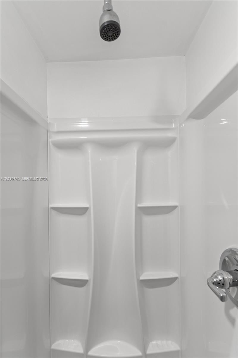 A white acrylic shower stall features built-in shelves and a chrome shower head — 3016 NW 22nd Ct # 3020, Miami FL 33142, MIAMI, FL