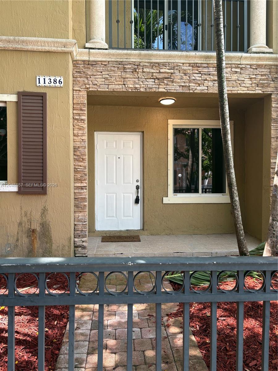 The exterior of a tan townhouse features a stone-accented entryway and a white front door — 11386 SW 230th Ter # 11386, Miami FL 33170, MIAMI, FL