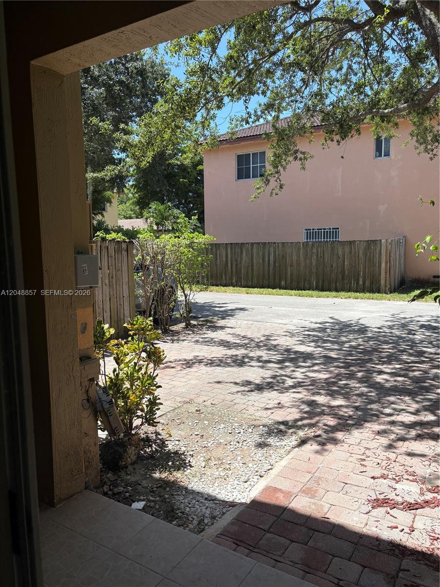 A view from a covered patio looking out toward a paved driveway and wooden fence — 11386 SW 230th Ter # 11386, Miami FL 33170, MIAMI, FL