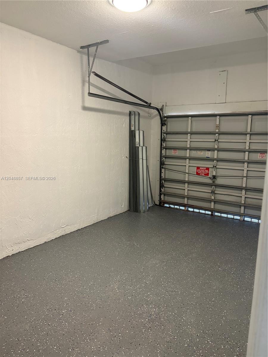 A garage with a speckled gray floor, white walls, and a metal sectional door — 11386 SW 230th Ter # 11386, Miami FL 33170, MIAMI, FL