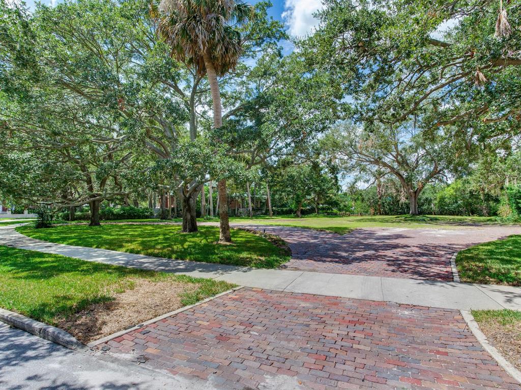 A brick driveway leads to a grassy lot shaded by large, mature oak trees — 5001 S SHORE CREST CIRCLE, TAMPA, FL