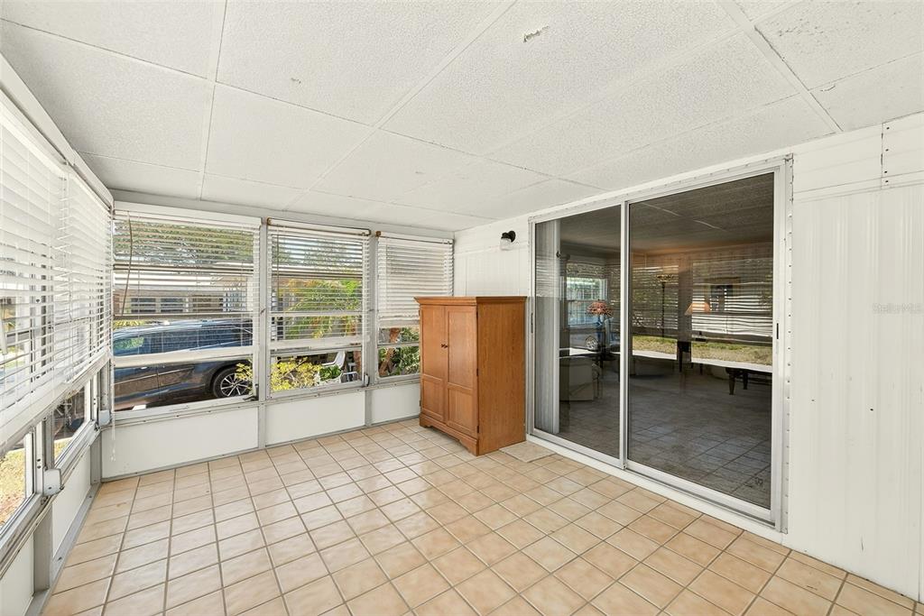 A sunroom with tiled flooring, large windows with blinds, and a sliding glass door — 94 SUGAR BEAR DRIVE UNIT 55, SAFETY HARBOR, FL