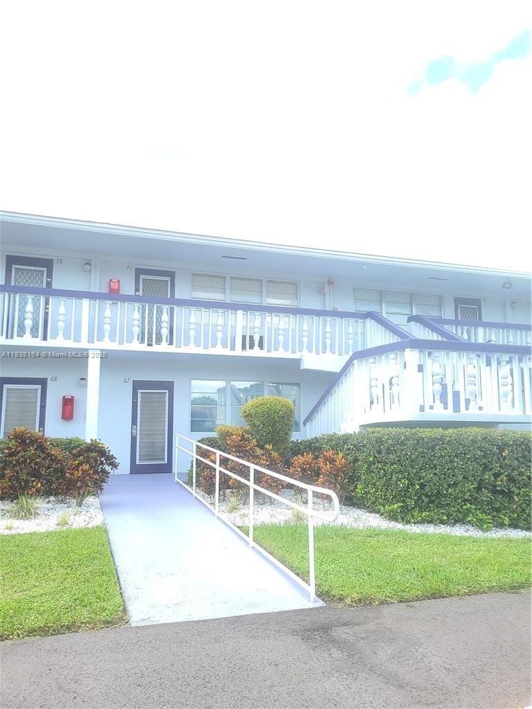 A two-story apartment building features a white exterior, purple railings, and a concrete wheelchair ramp — 82 Oakridge G # 82, Deerfield Beach FL 33442, DEERFIELD BEACH, FL