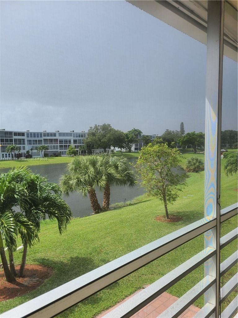 A view of a lake and green lawn from a screened-in balcony — 82 Oakridge G # 82, Deerfield Beach FL 33442, DEERFIELD BEACH, FL
