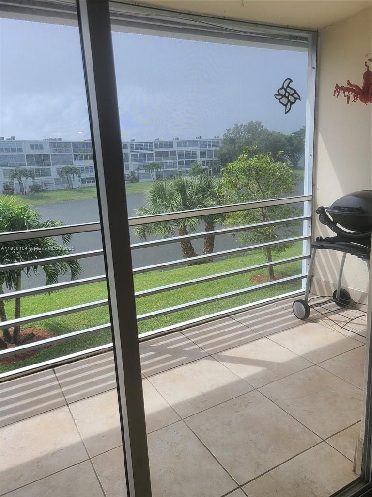 A balcony with tiled flooring, a metal railing, and a small grill overlooking a lake — 82 Oakridge G # 82, Deerfield Beach FL 33442, DEERFIELD BEACH, FL