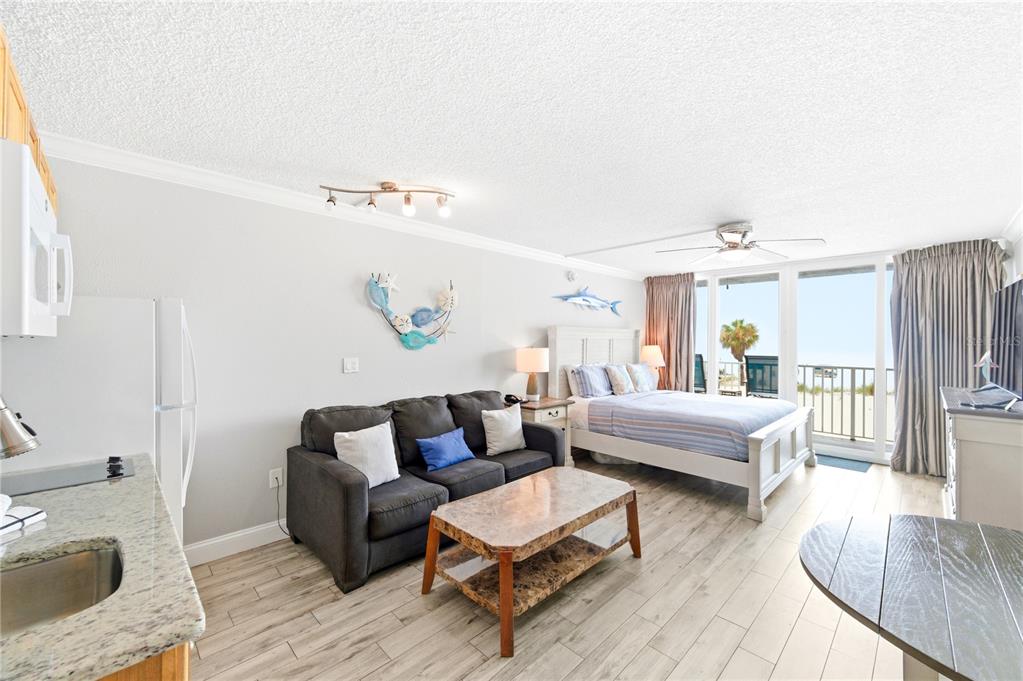 A studio apartment features a kitchenette, a sofa, a bed, and a balcony with beach views — 9980 GULF BOULEVARD UNIT 211, ST PETERSBURG, FL