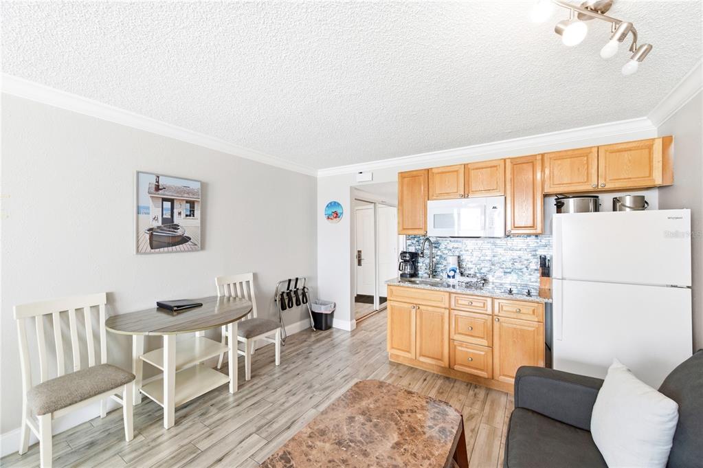 A small kitchen with light wood cabinets and a dining area with two chairs — 9980 GULF BOULEVARD UNIT 211, ST PETERSBURG, FL