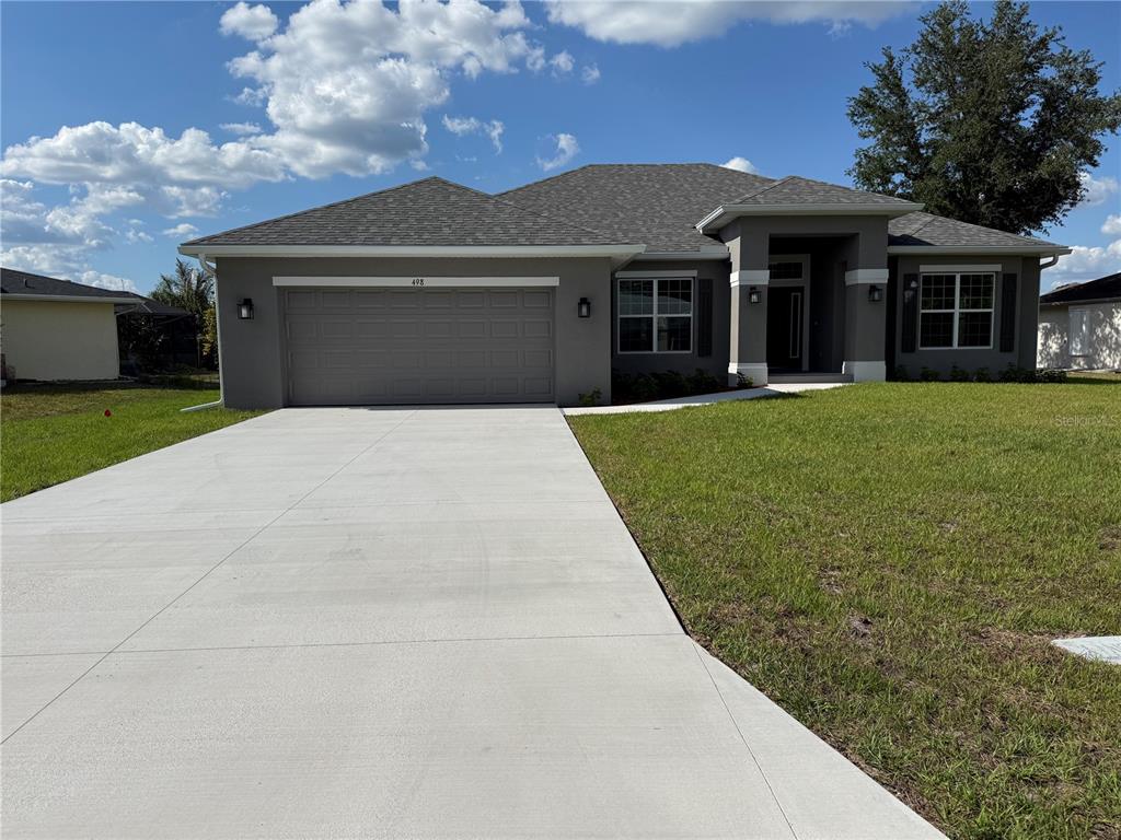 A gray single-story house features a two-car garage, a concrete driveway, and a covered entryway — 498 SANTIGUAY STREET, PUNTA GORDA, FL