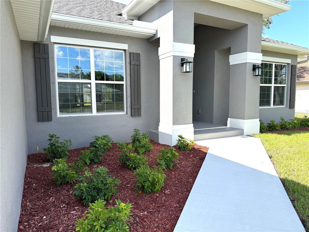 The exterior of a gray house features white trim, dark shutters, and a landscaped bed — 498 SANTIGUAY STREET, PUNTA GORDA, FL