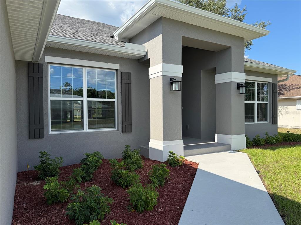 A gray stucco house exterior features white trim, dark shutters, and a concrete walkway — 498 SANTIGUAY STREET, PUNTA GORDA, FL