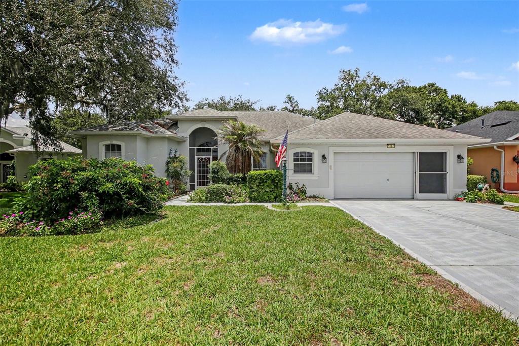 A single-story house with a white stucco exterior, a two-car garage, and a landscaped front yard — 5127 AURORA DRIVE, LEESBURG, FL