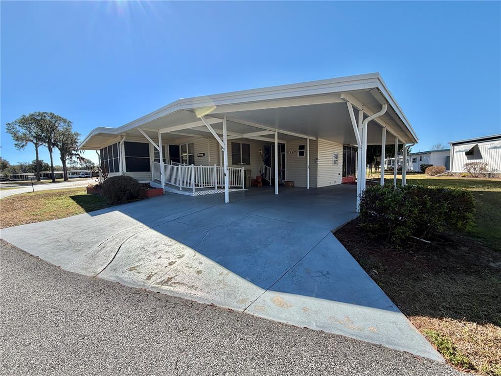 A mobile home with a large attached carport and a white wheelchair ramp — 353 PALO VERDE DRIVE, LEESBURG, FL